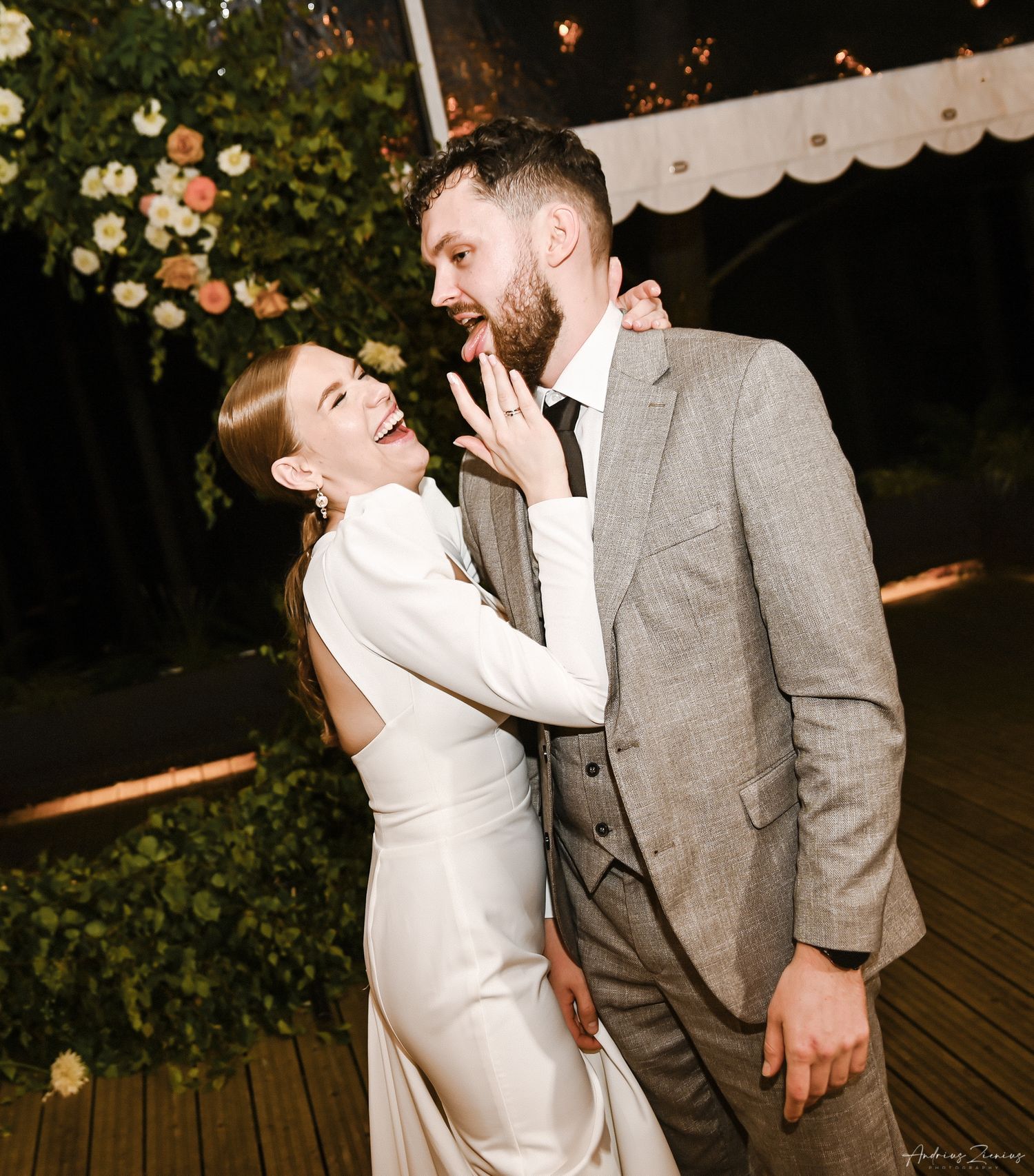A candid reception moment showing a couple sharing laughter against floral decorations.