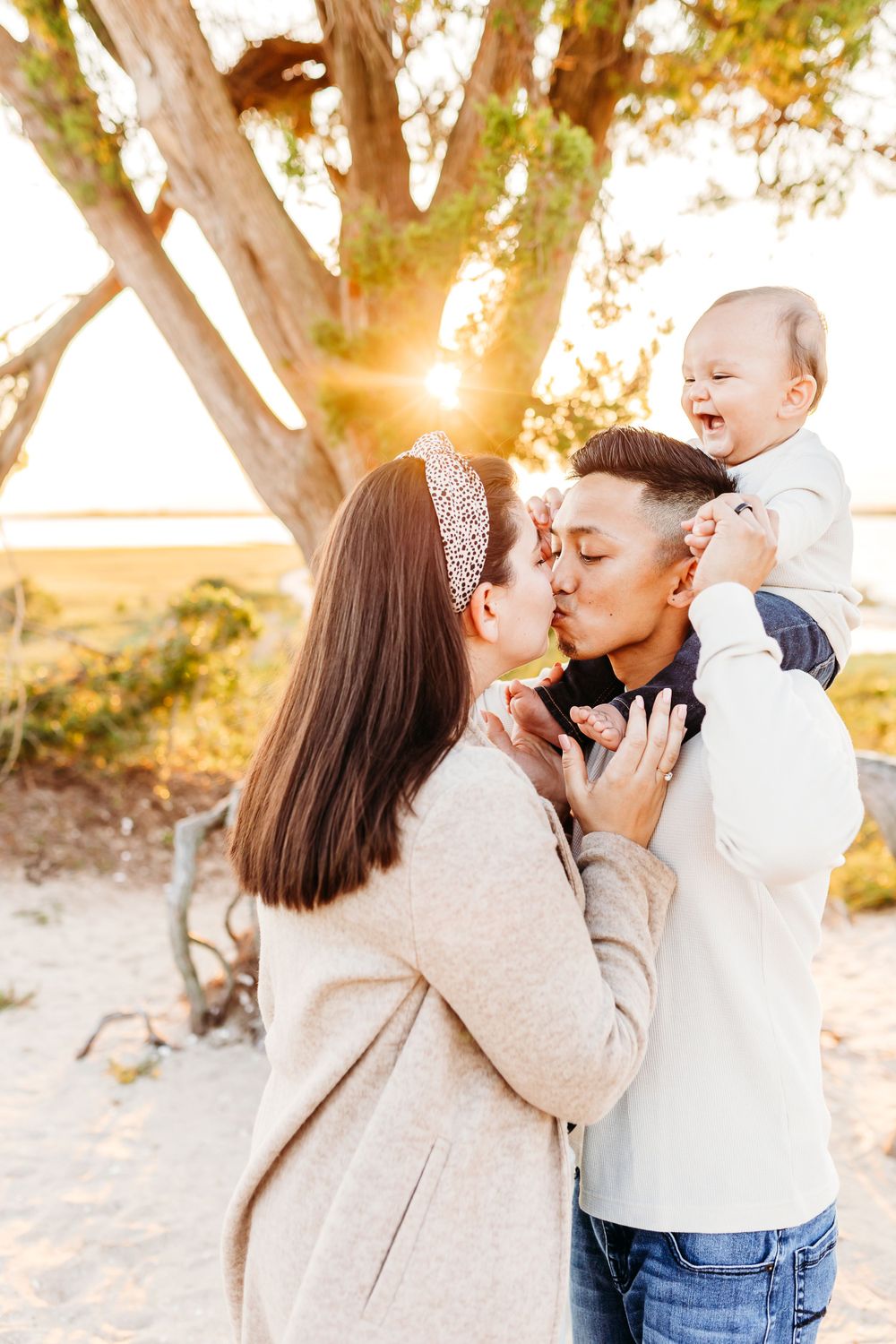 Romantic couple shares tender moments during sunset photo session at beach with trees in background.