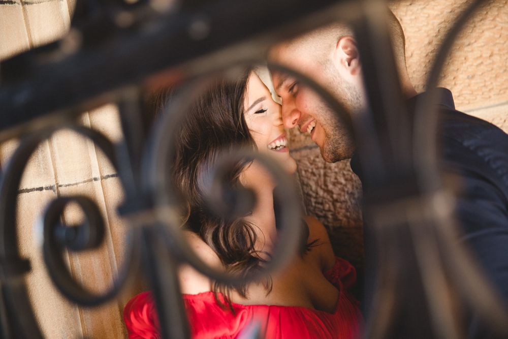 A couple shares an intimate moment seen through decorative iron railings.