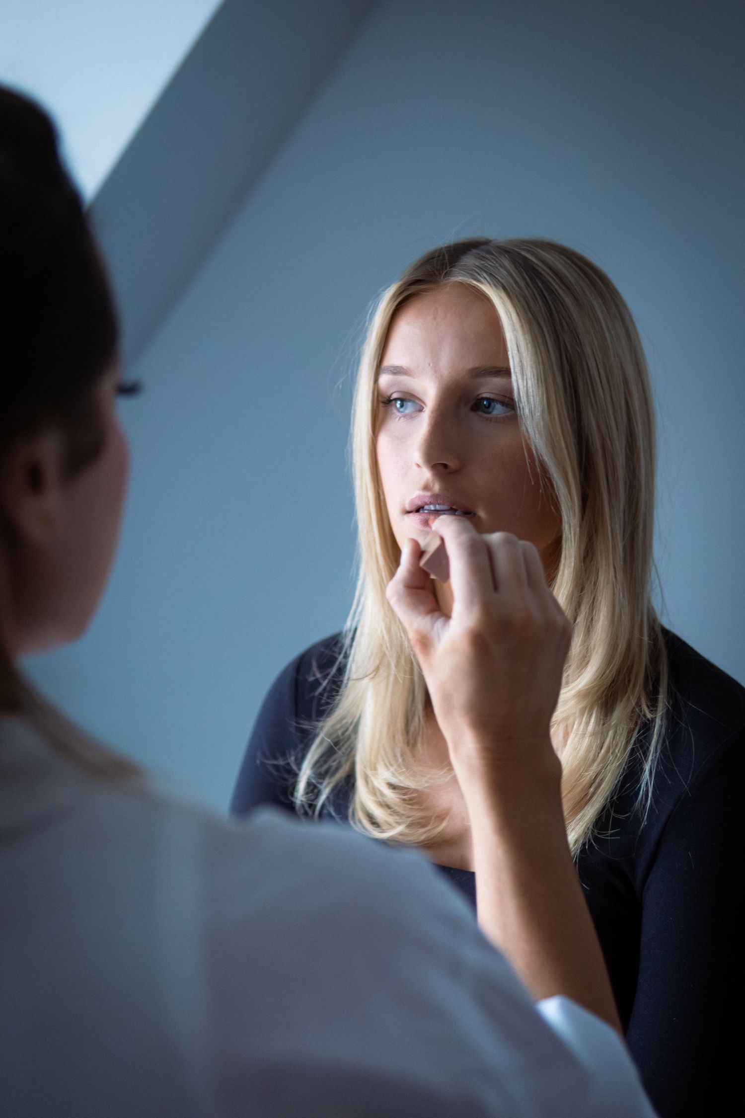 Kvinna får makeup lagd av makeupartist i mjukt ljus. Hon har långt blont hår och svart topp.
Fotograf: Gabriel Alenius, Falun