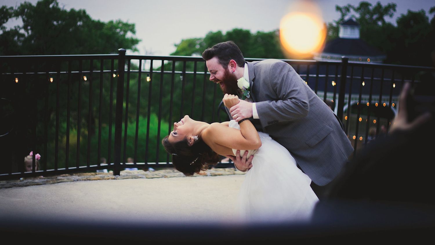A romantic dip dance at a wedding reception with string lights glowing in the background.