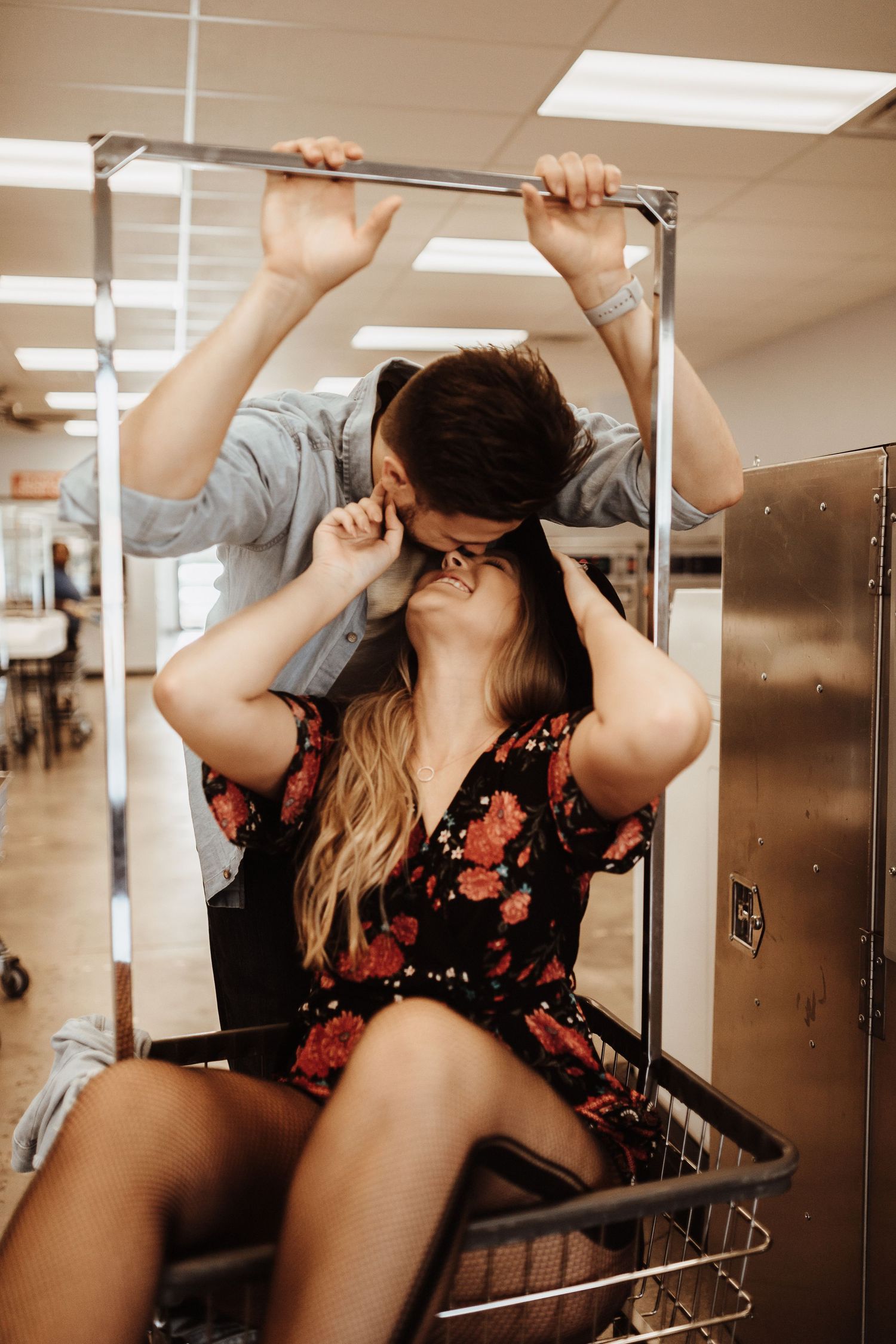 Couple sharing a romantic moment in a luandry cart at a brightly lit laundry mat.