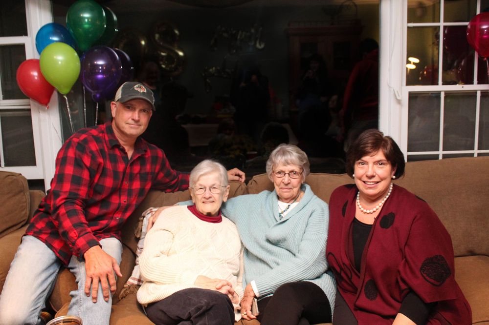 Group photo with colorful balloons decorating the window behind the couch.