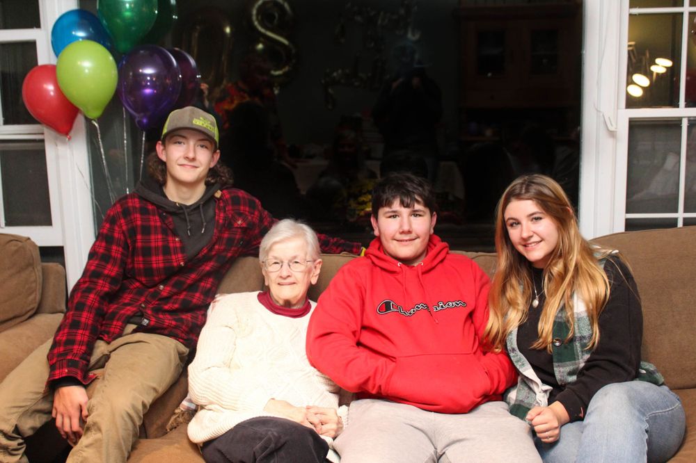 Group photo on a couch with colorful balloons decorating the window.