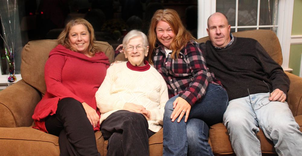 Family members posed together on a brown couch for a casual portrait.