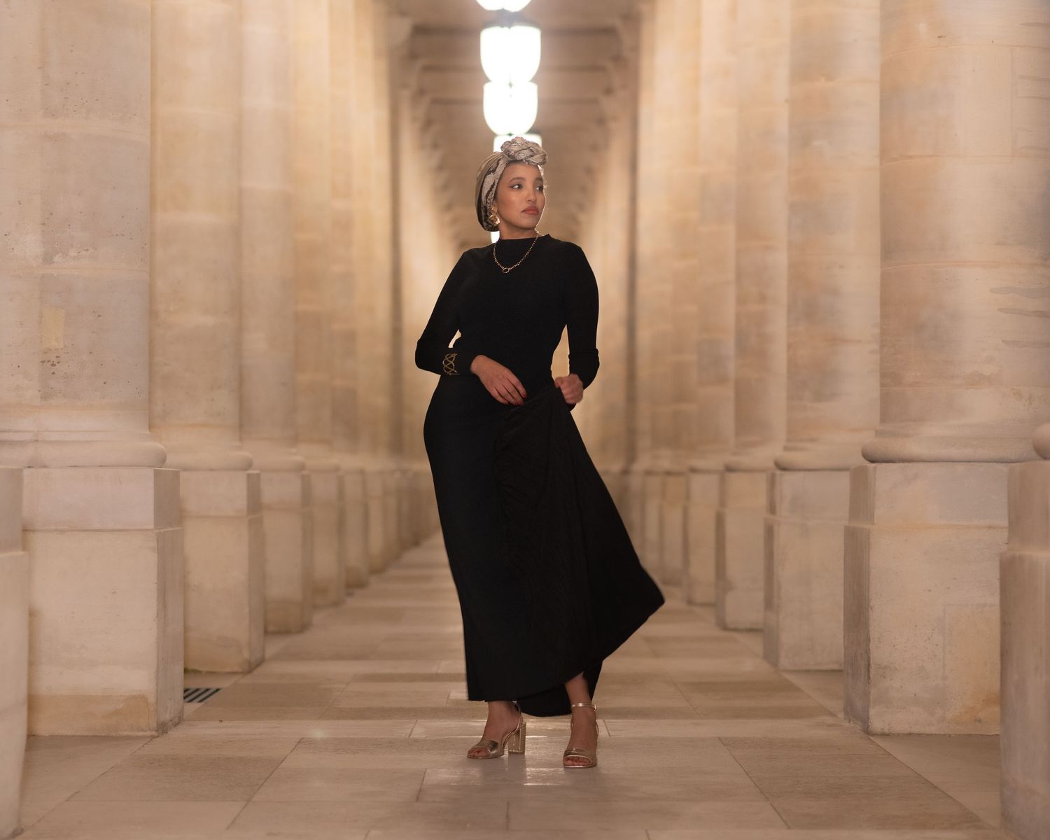 Long architectural corridor with stone columns and dramatic lighting.