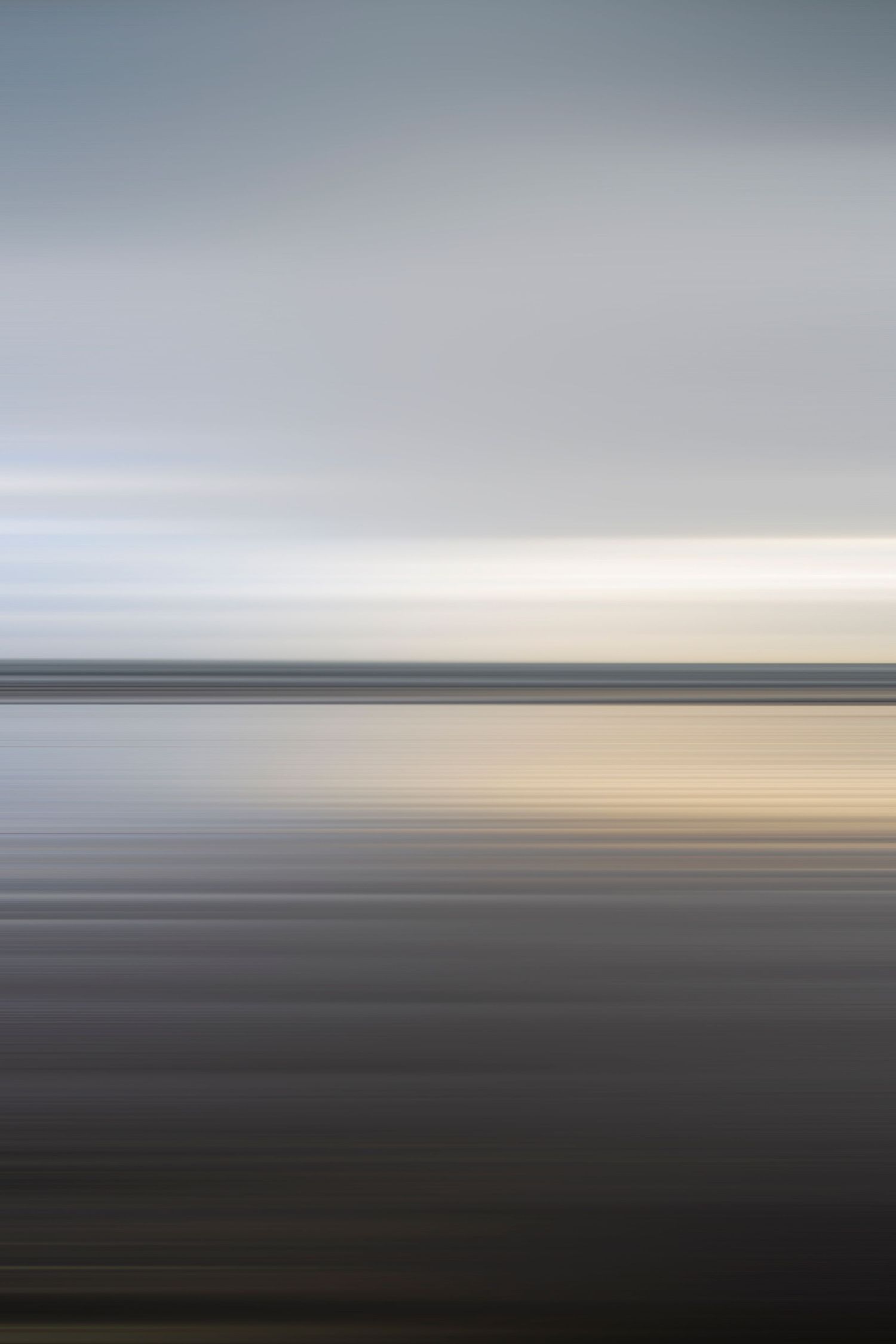 A minimalist seascape with a long-exposure effect, creating smooth, horizontal lines and a subtle transition from dark foreground to a light