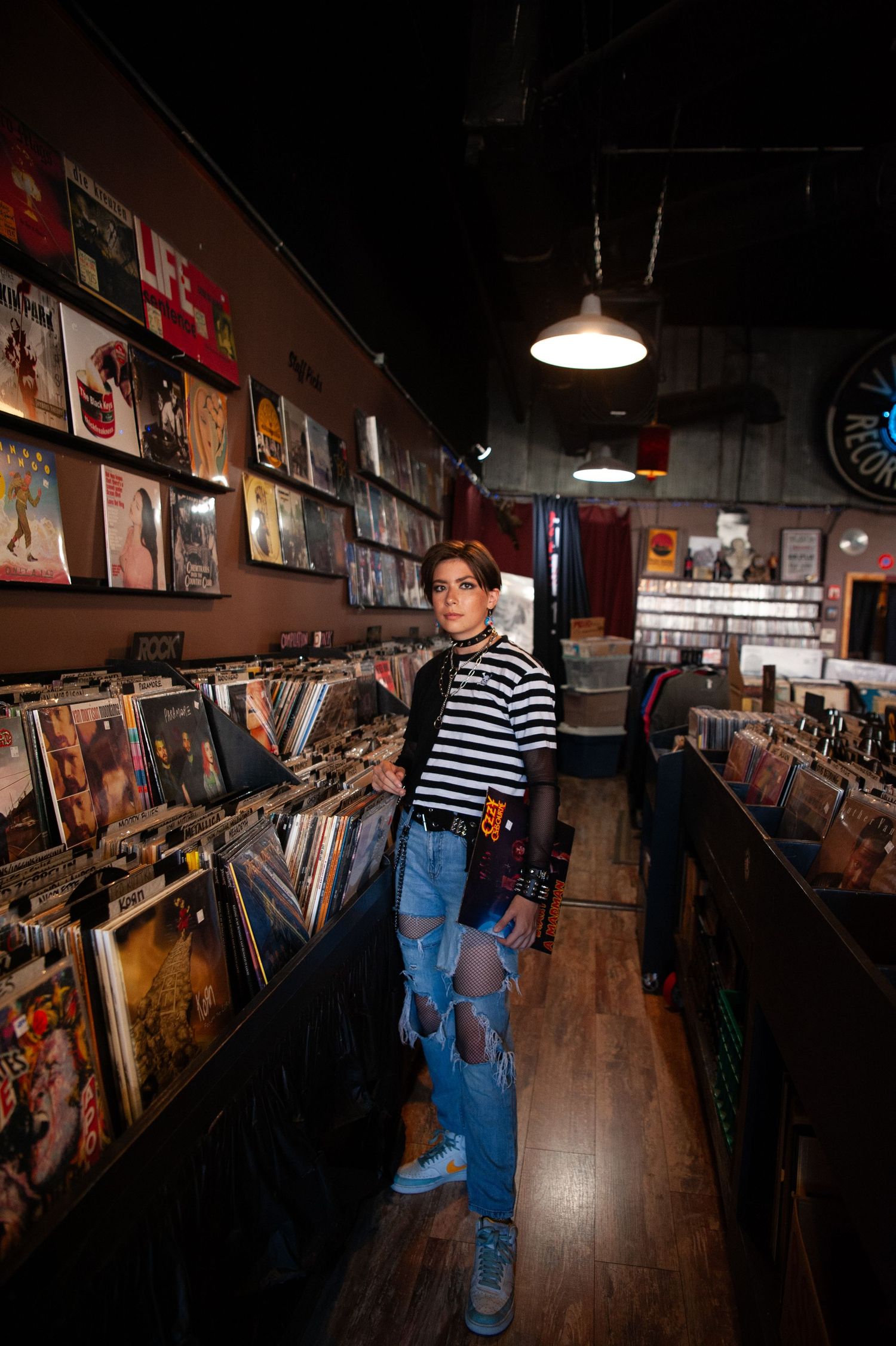 Interior of a record store with vinyl albums displayed on wooden shelves and pendant lighting.