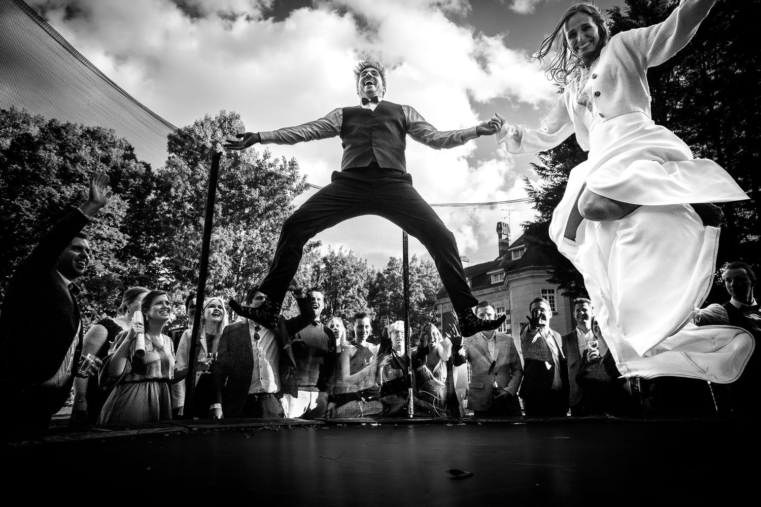 Bruidskoppel op de trampoline springend terwijl de suite errond staat