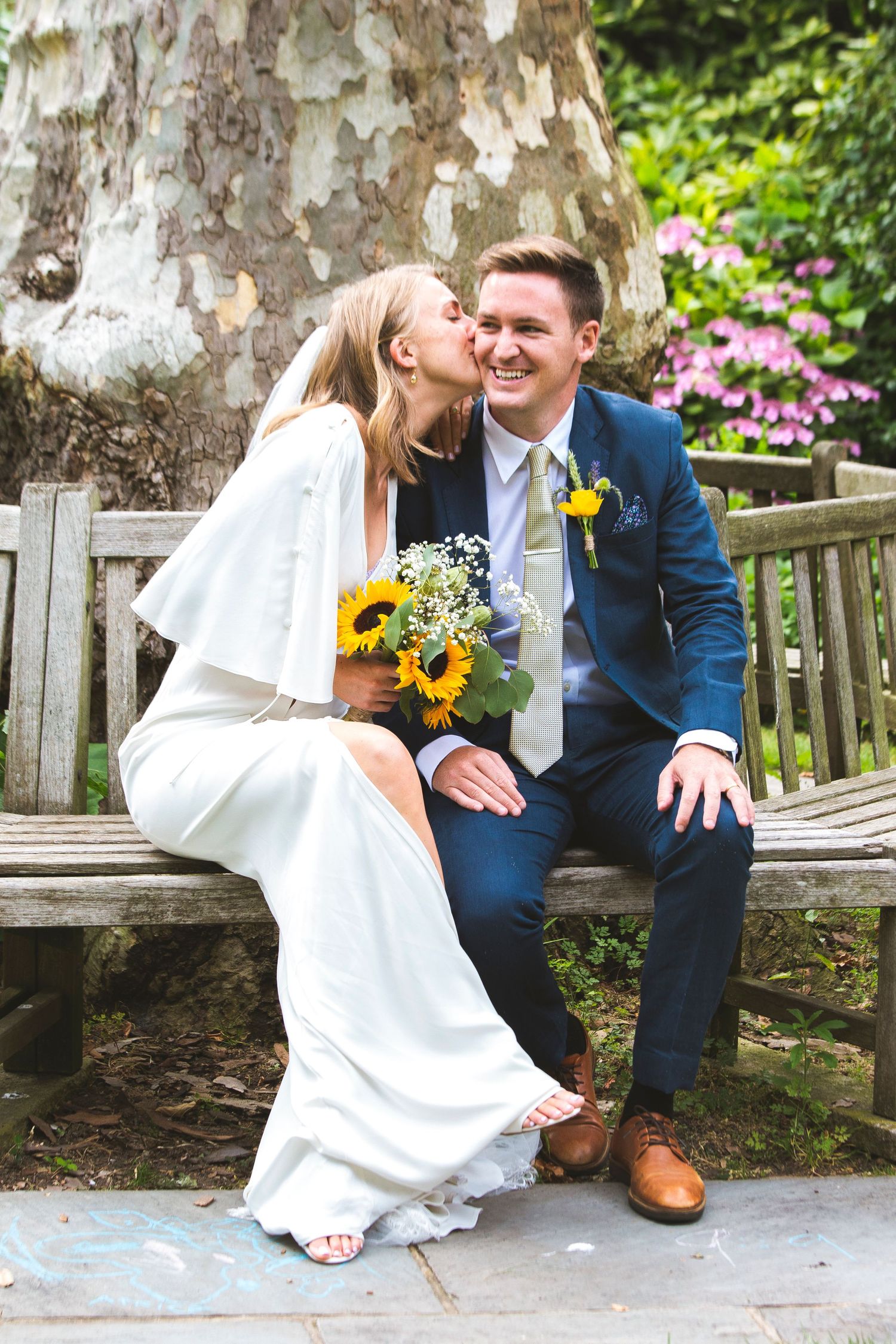 Bride kissing her groom, holding a sunflowers bouquet