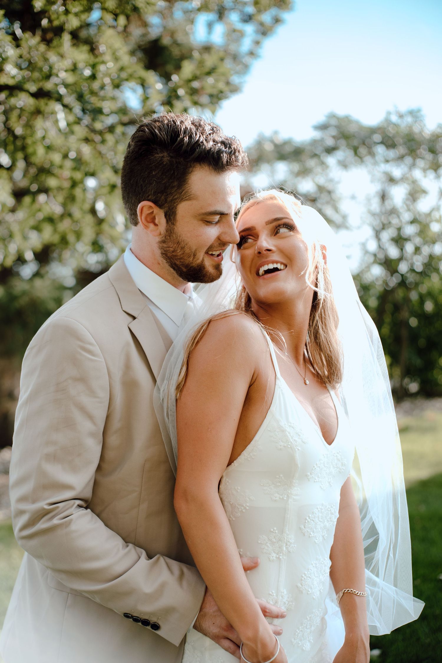 A tender moment between newlyweds sharing laughter during their outdoor wedding photoshoot.