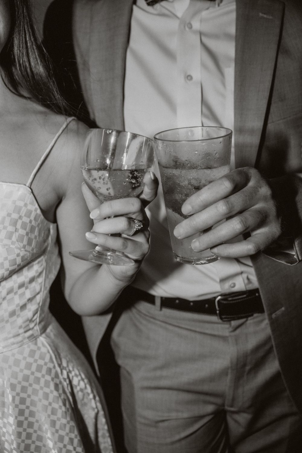 A couple clinks their glasses together in black and white