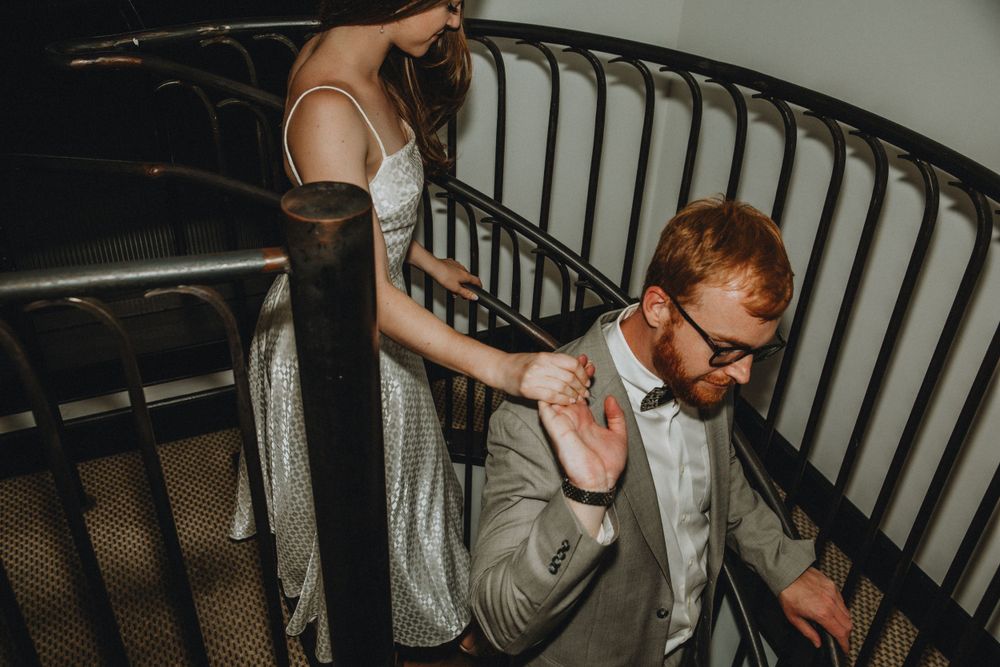 A man leads a woman down a spiral staircase