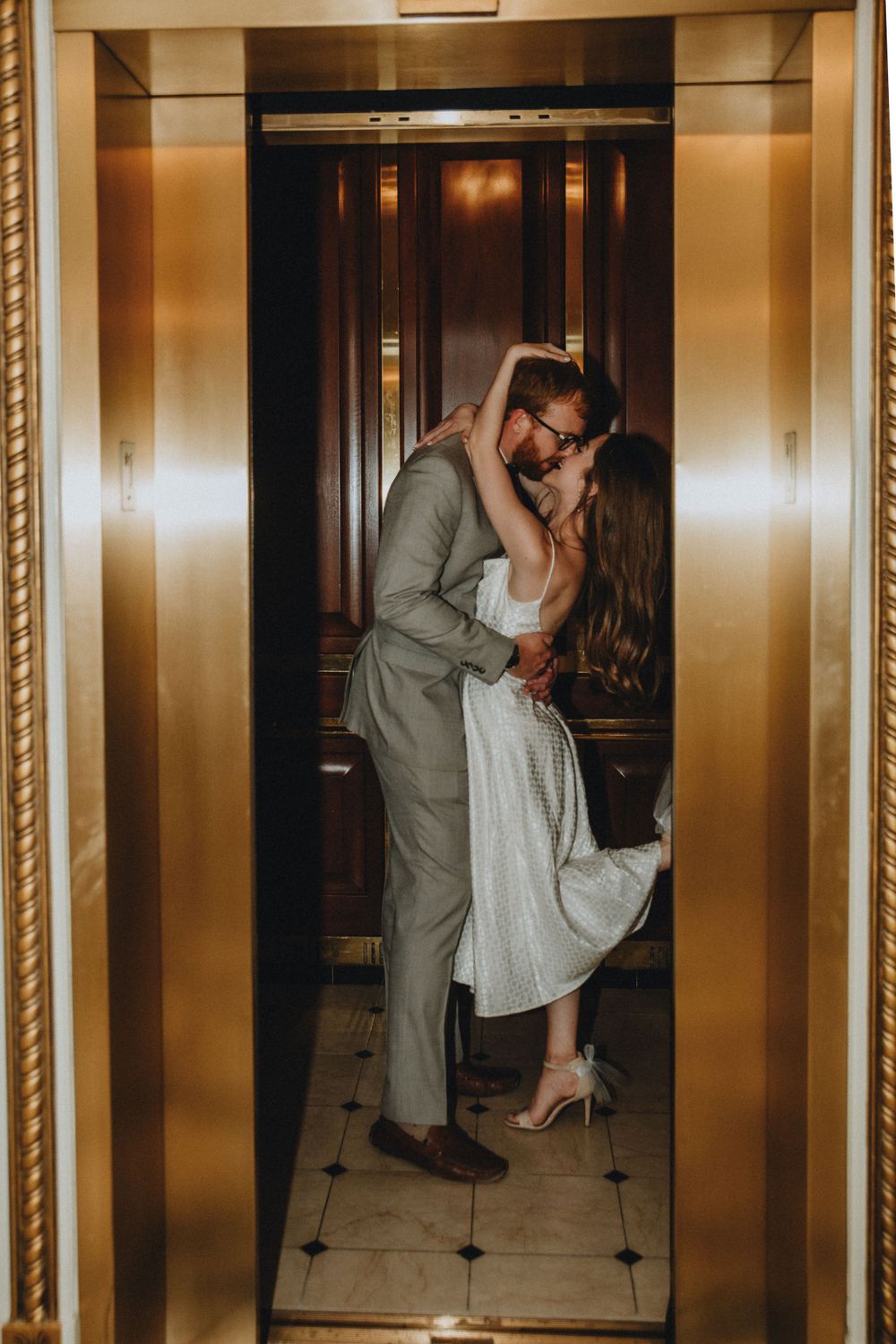 A couple poses in an elevator as the doors close