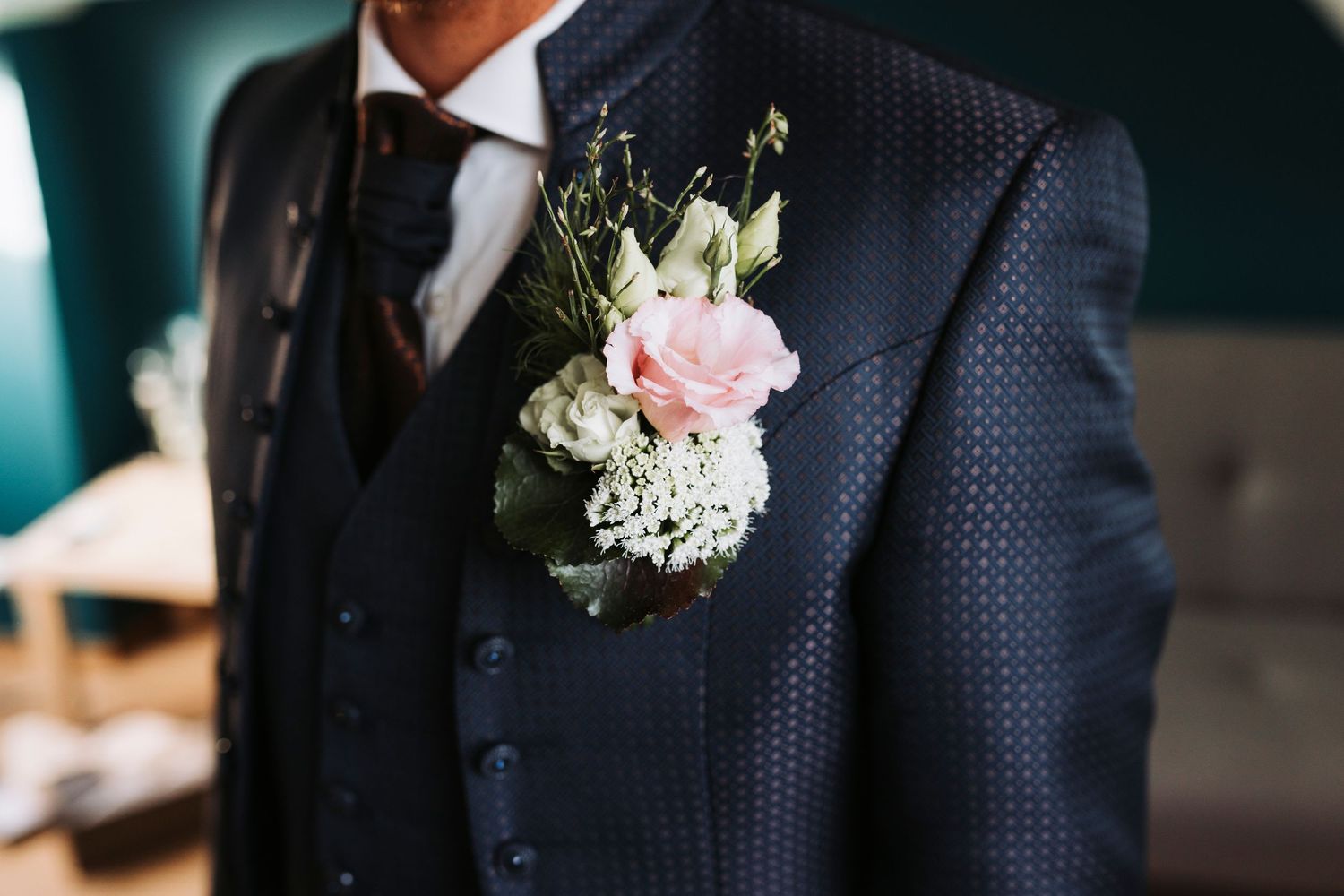 Close-up of groom's navy suit with pink and white floral boutonniere.