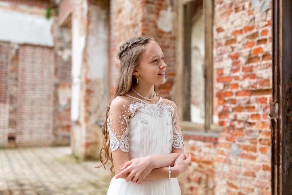 Romantic portrait against brick wall featuring delicate white lace details and braided hair.
