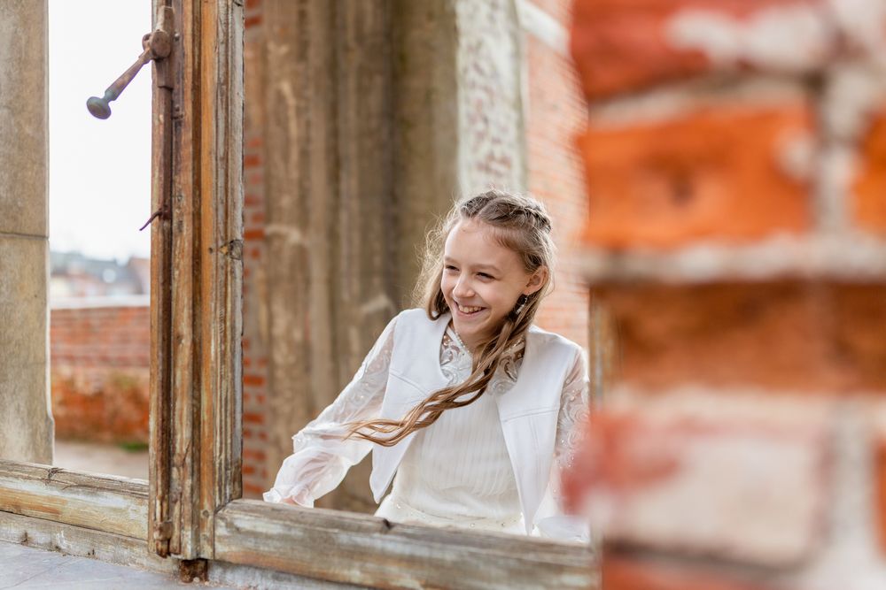 Joyful scene by an old window frame with someone wearing white and showing genuine emotion.