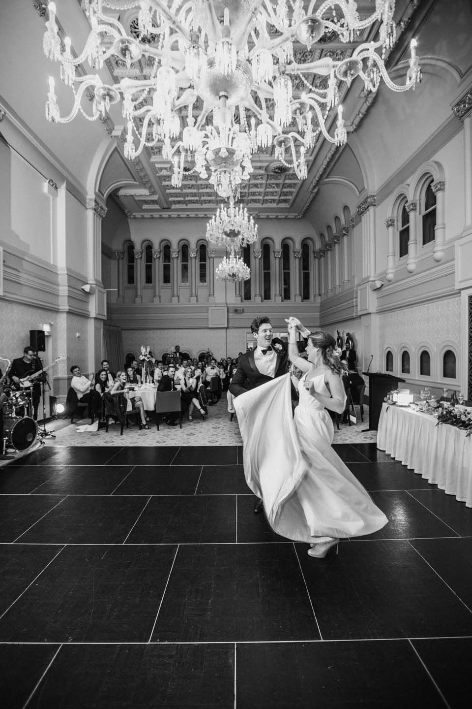 Elegant ballroom wedding reception with crystal chandeliers and dancing.
