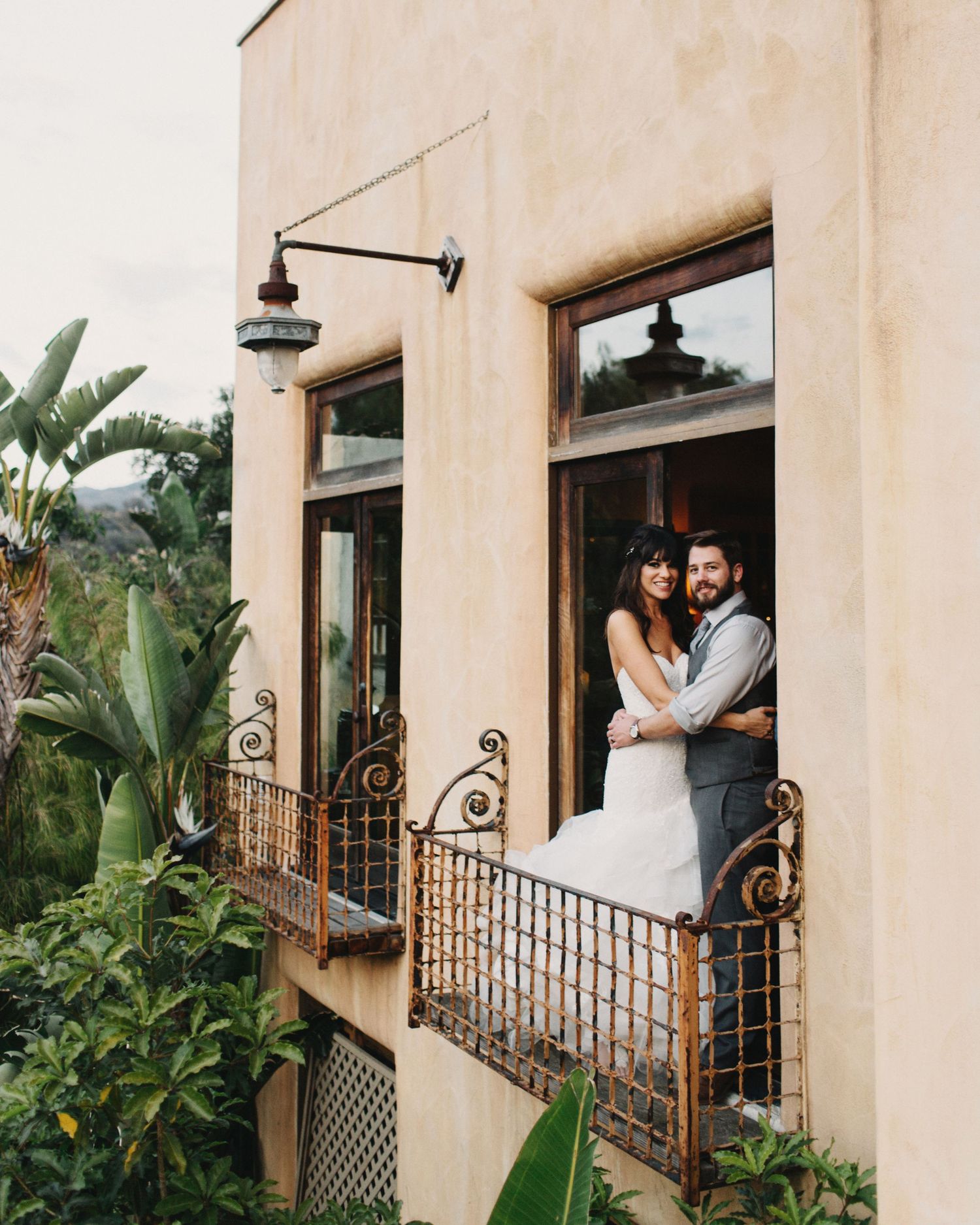 Romantic destination wedding portrait of a bride and groom sharing an intimate embrace on a historic balcony.
