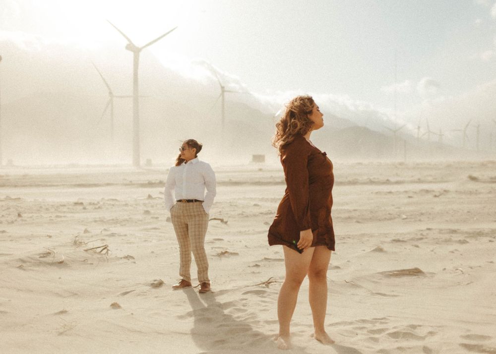 engaged couple at the windmills in Palm Springs, stare off into the sunset