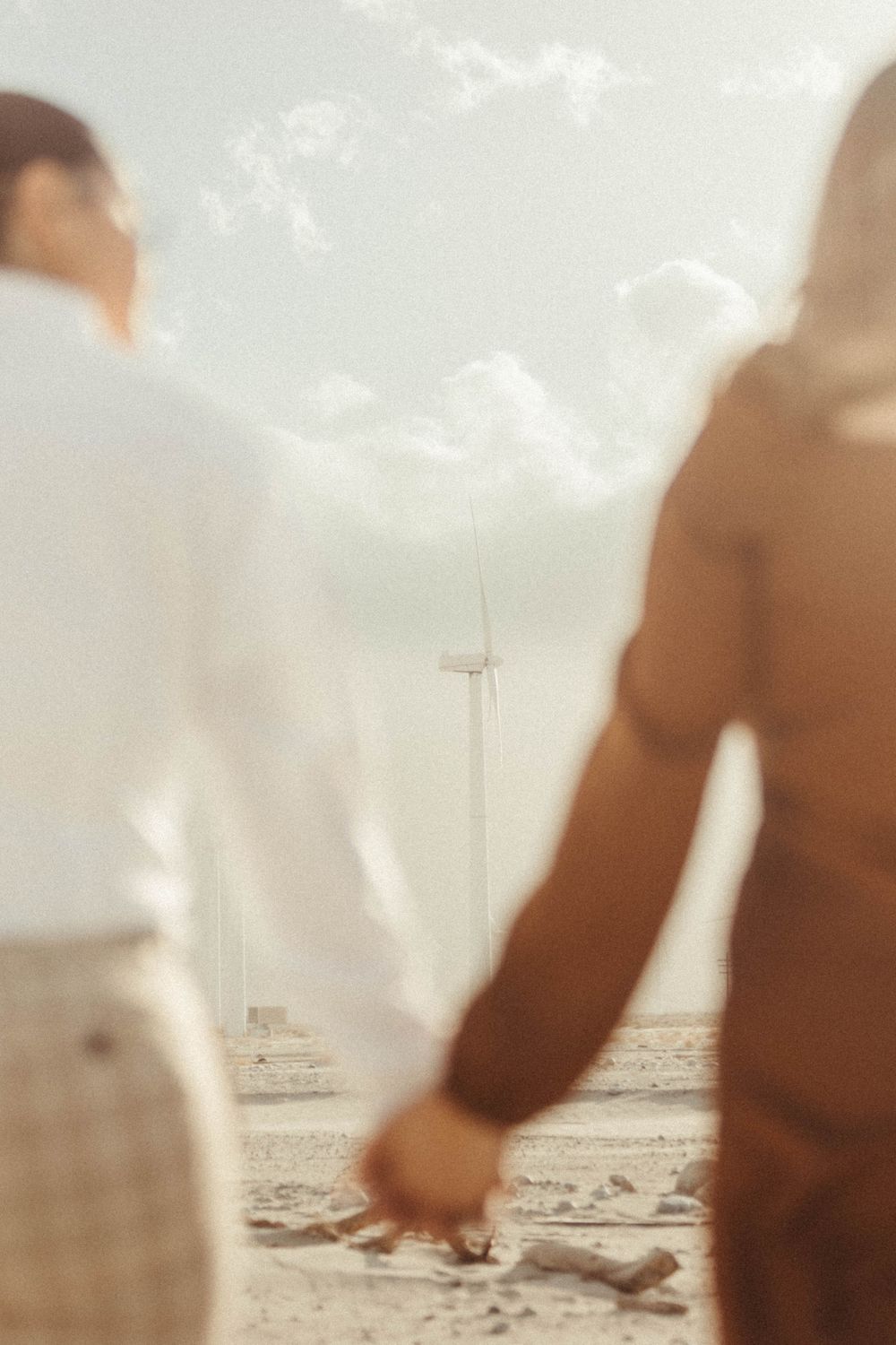 engaged couple hold hands, the main focus is on the Palm Springs windmills in between their hands and arms