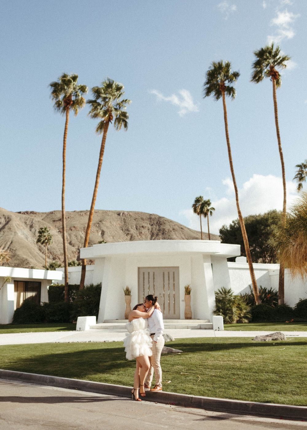 Two women embrace in front of a Mid-Century Modern Home in Palm Springs