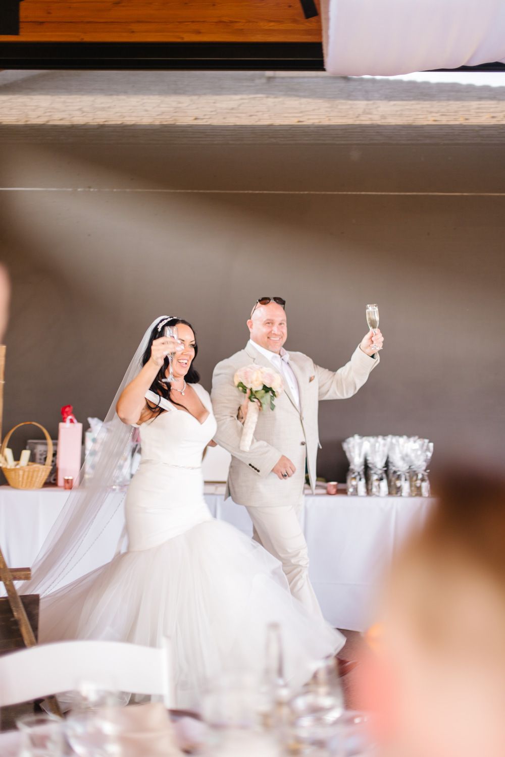 Wedding reception setup with guests in white attire seated at decorated tables.