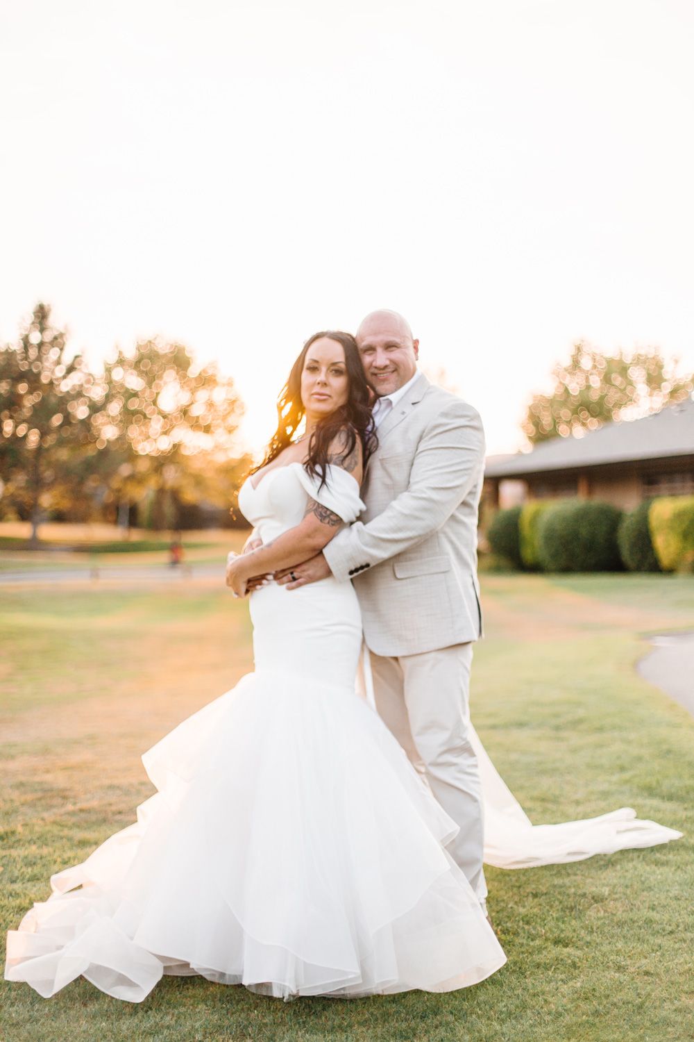 Sunset wedding portraits on a grassy lawn showing romantic poses and flowing white dress.