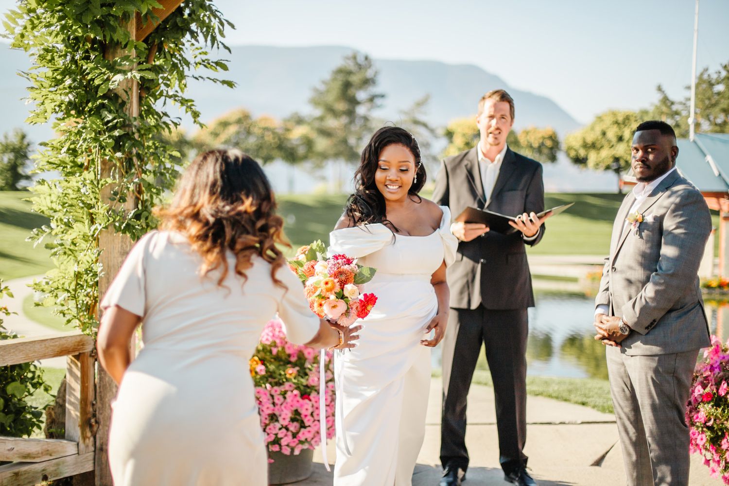 A beautiful outdoor wedding ceremony unfolds with pink floral decorations and natural scenery.