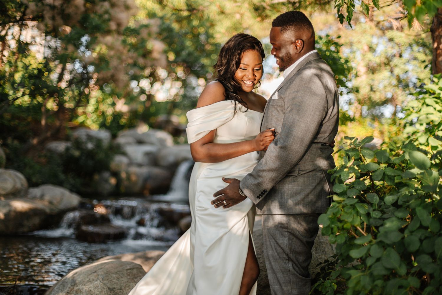 A couple shares intimate moments during their wedding photoshoot near a garden waterfall.