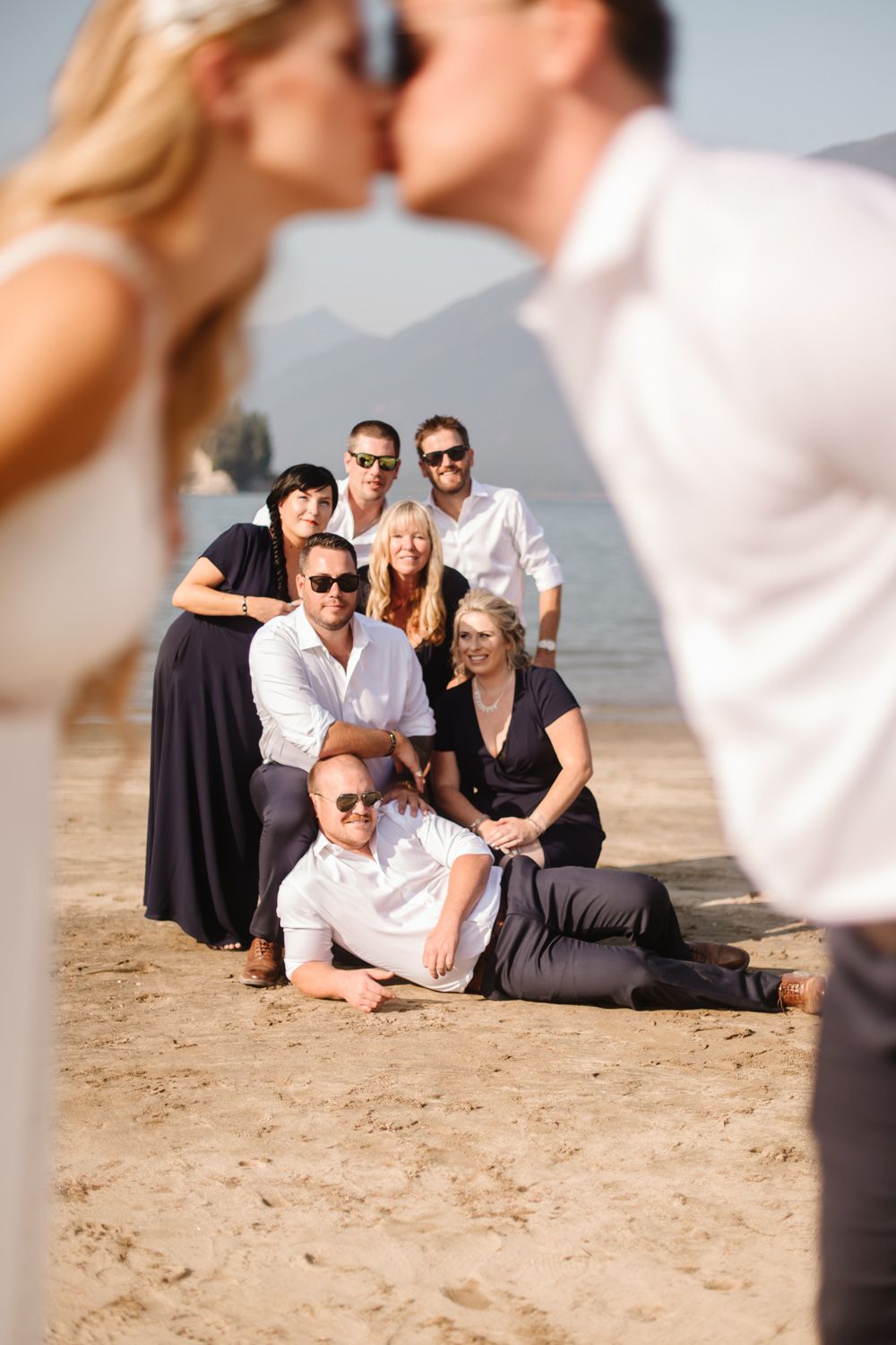 Wedding party relaxing on the beach in casual poses during photo session.