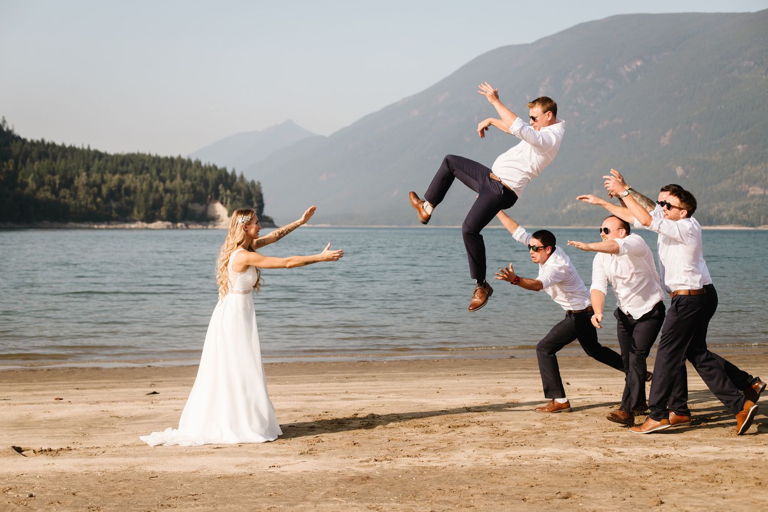 Creative action shot of wedding party falling like dominoes on beach.