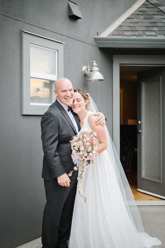Wedding couple sharing joyful moments outside a modern grey building.