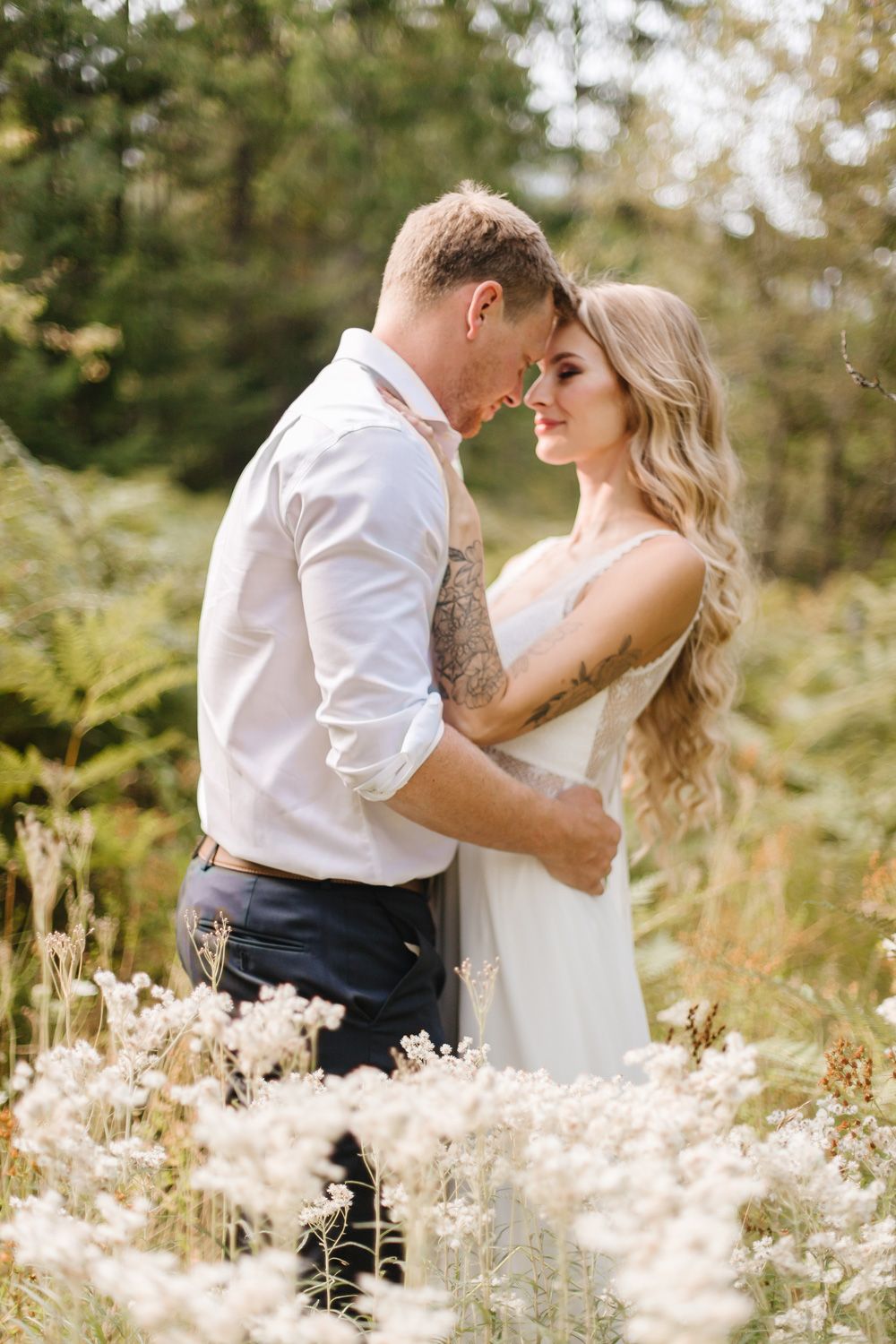 Couple embracing in a wildflower field during romantic wedding photoshoot.