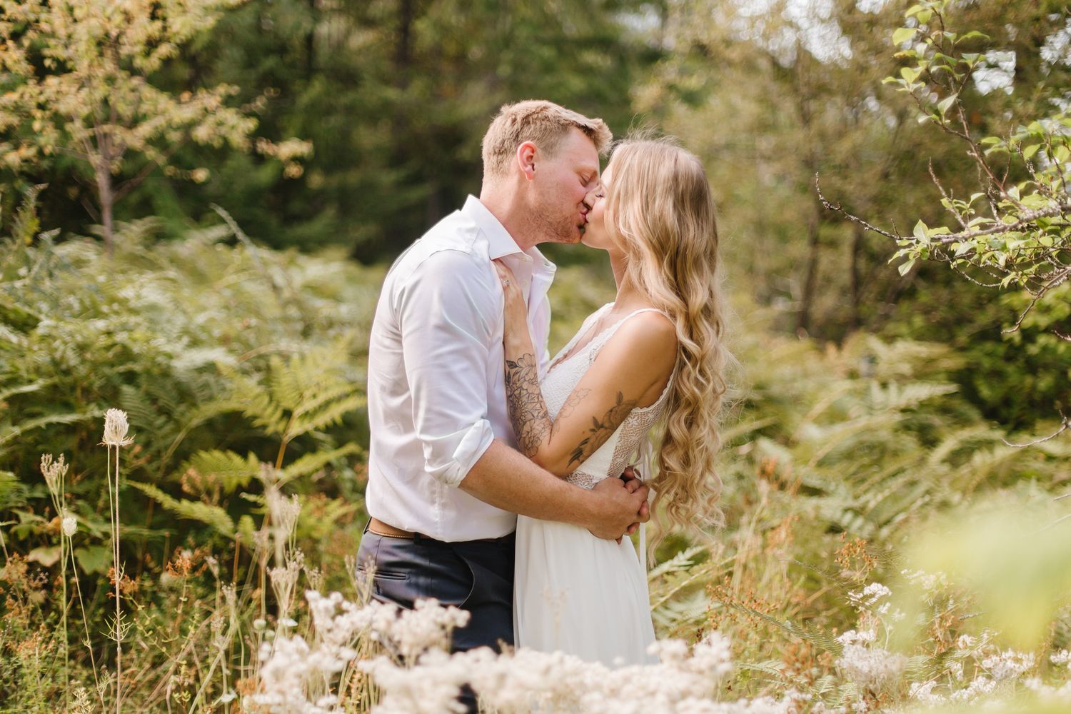Romantic outdoor wedding portraits among blooming summer flowers and greenery.