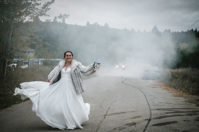 A bride dances joyfully on a foggy road in her flowing white wedding dress.