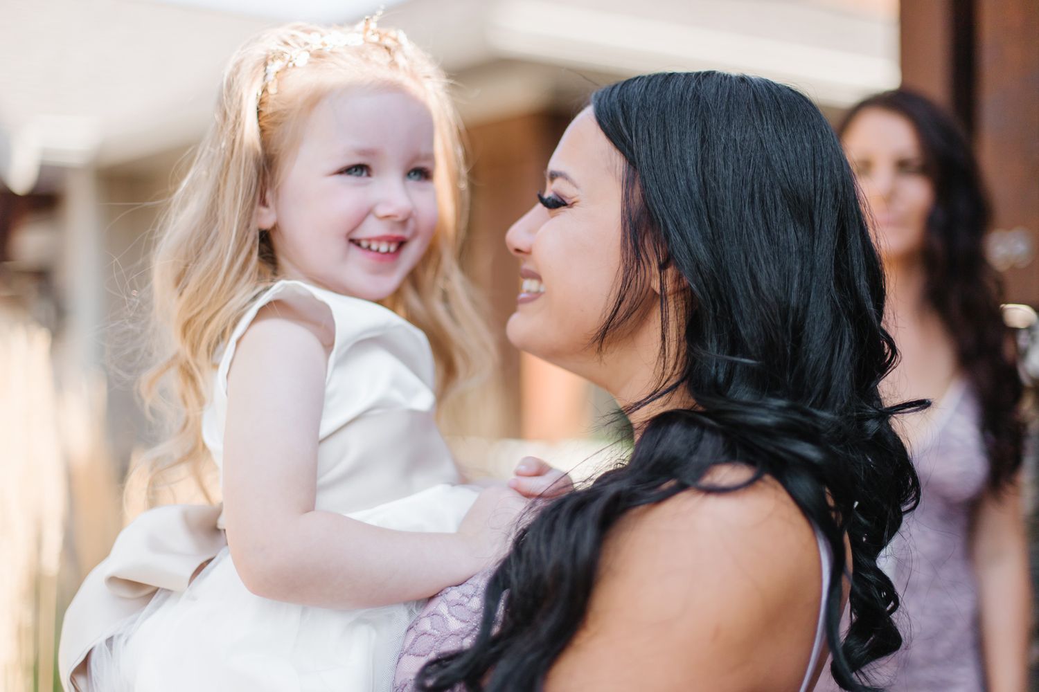 A touching moment between a flower girl in white and wedding party member.