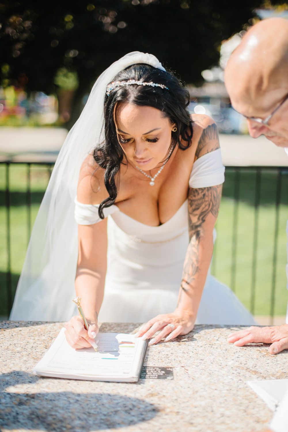 Close-up shots of someone signing documents on a stone surface outdoors.