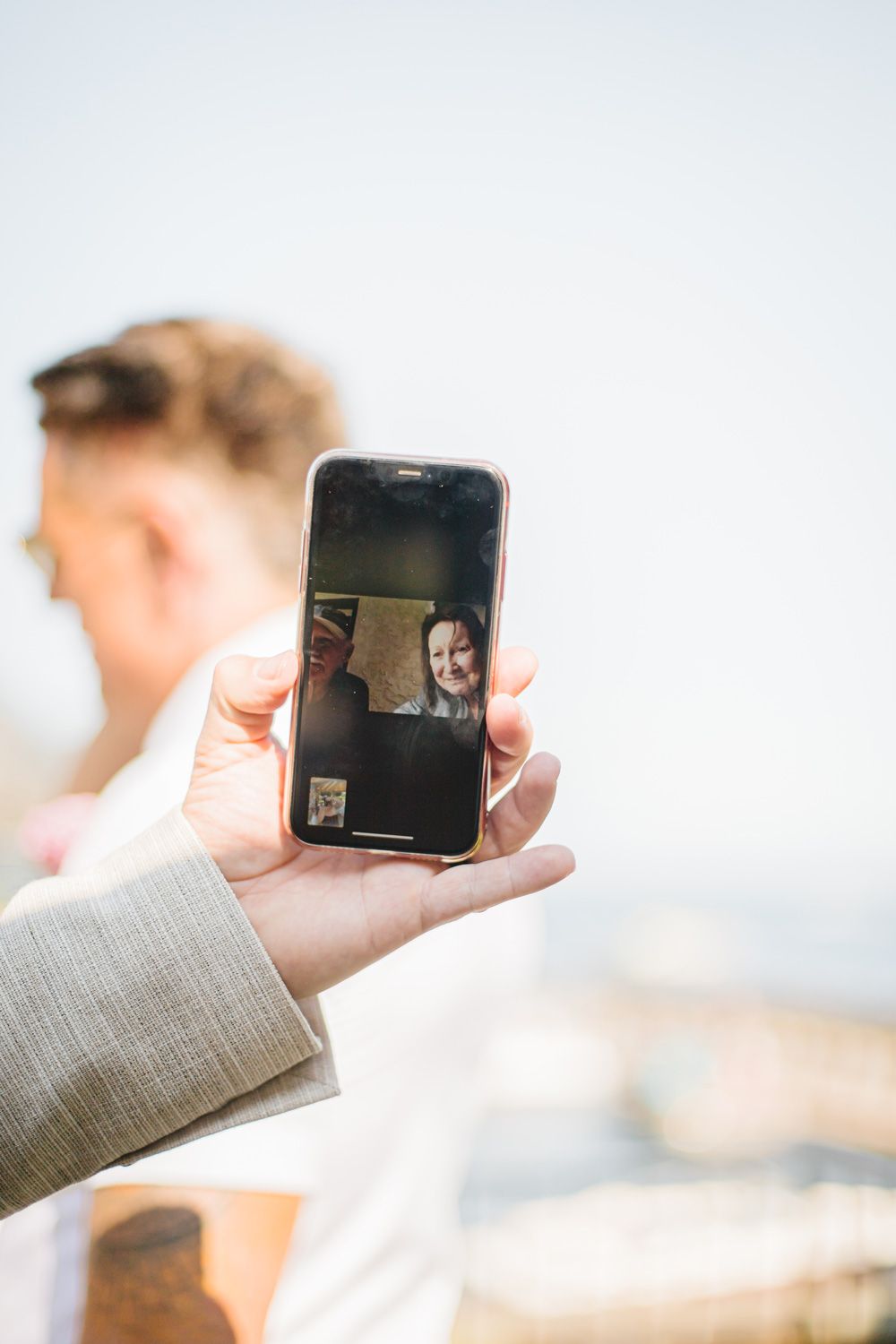 Hand holding a phone to capture photos during an outdoor event.
