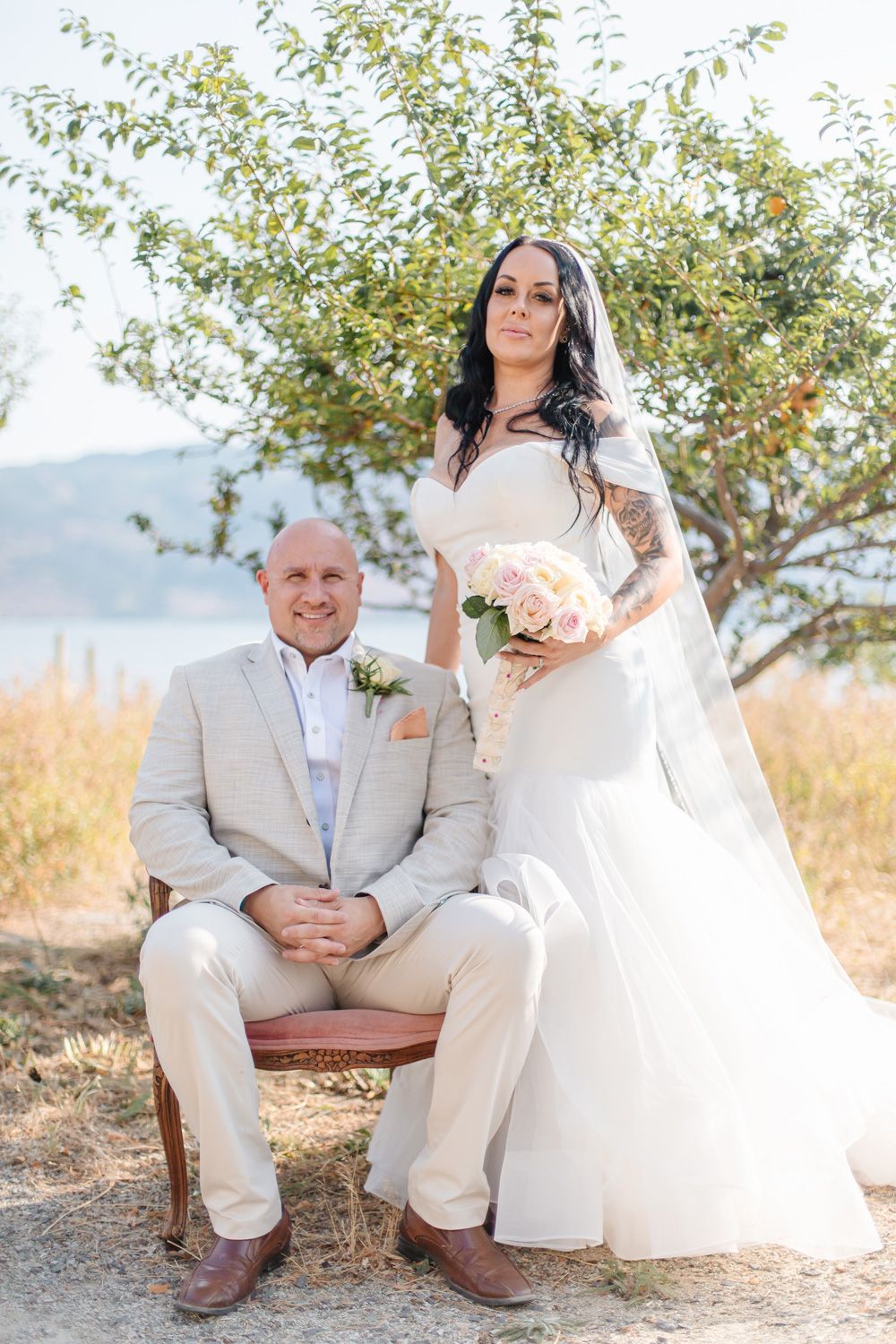 Romantic outdoor wedding portraits taken in a field with golden grass and trees.