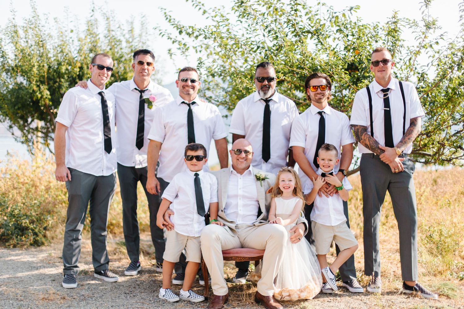 Wedding party members in coordinated attire pose together outdoors.
