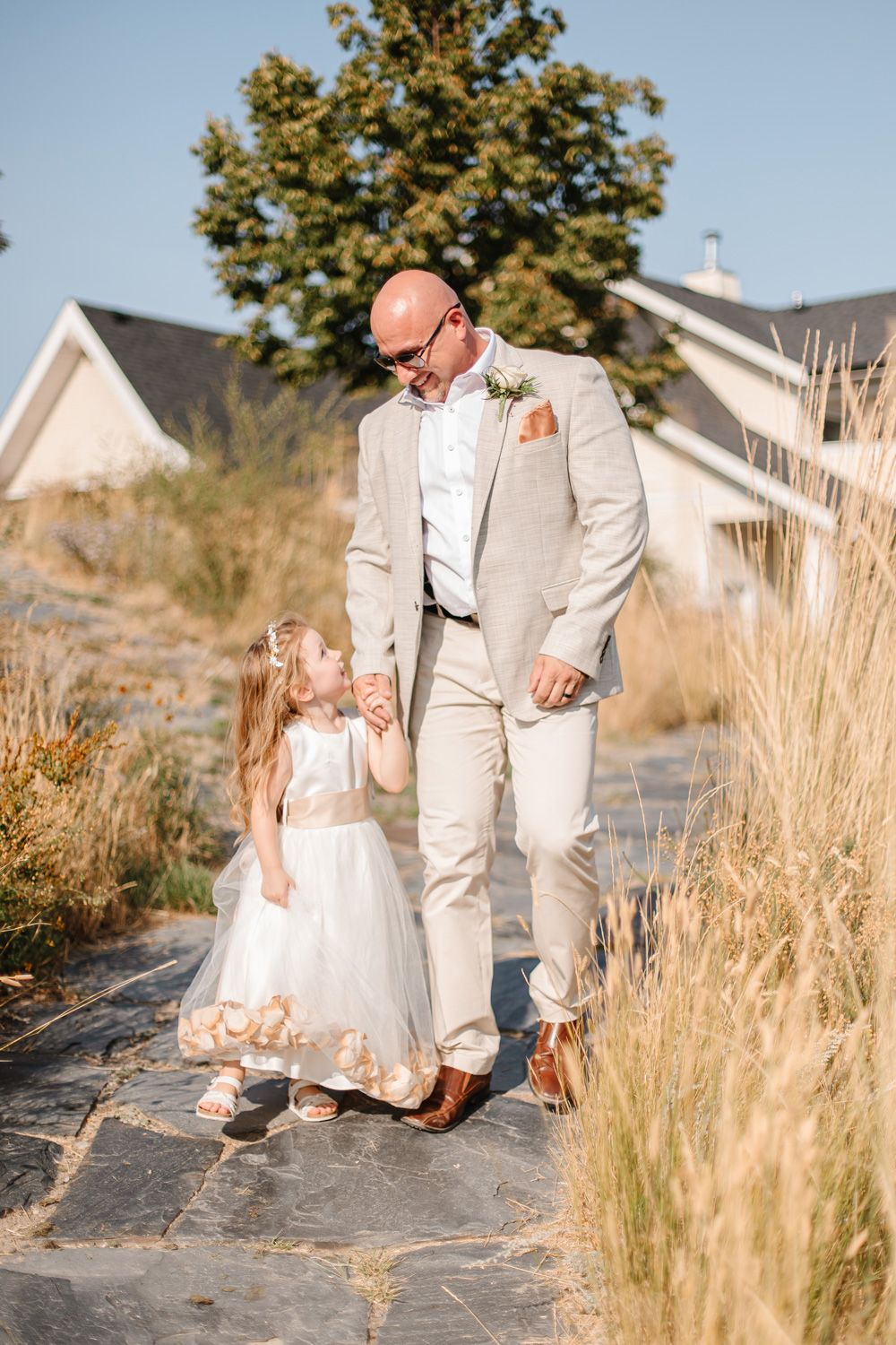 Romantic wedding photos taken in tall grass with mountains and sunlight creating a dreamy atmosphere.
