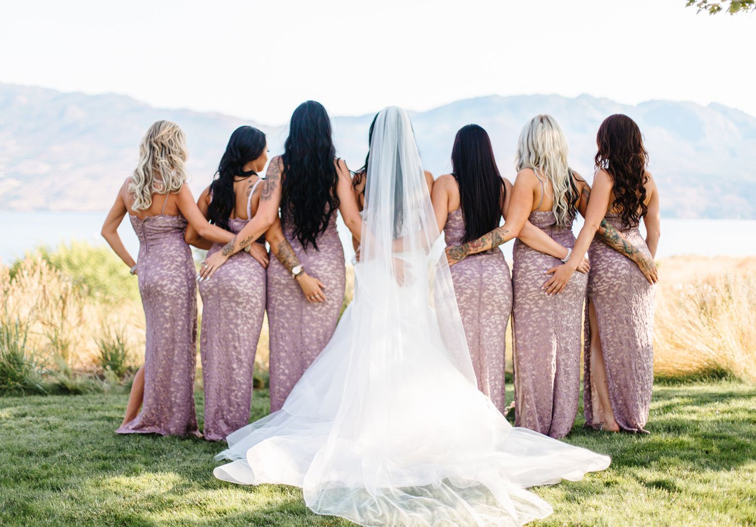 Wedding party poses in pink sequined dresses against a scenic mountain backdrop.