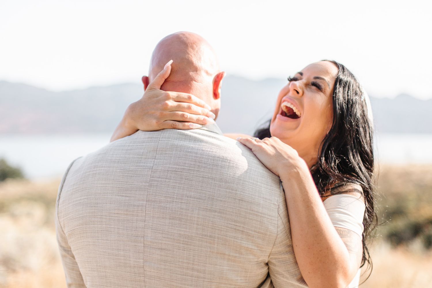Joyful wedding couple sharing intimate moments against mountain scenery.