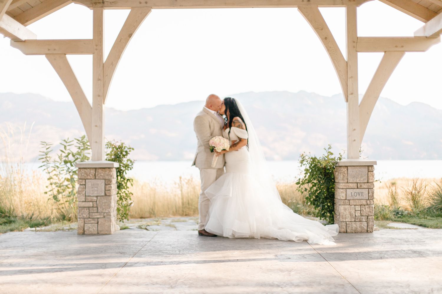 Elegant covered patio with white pillars framing mountain views at wedding venue.