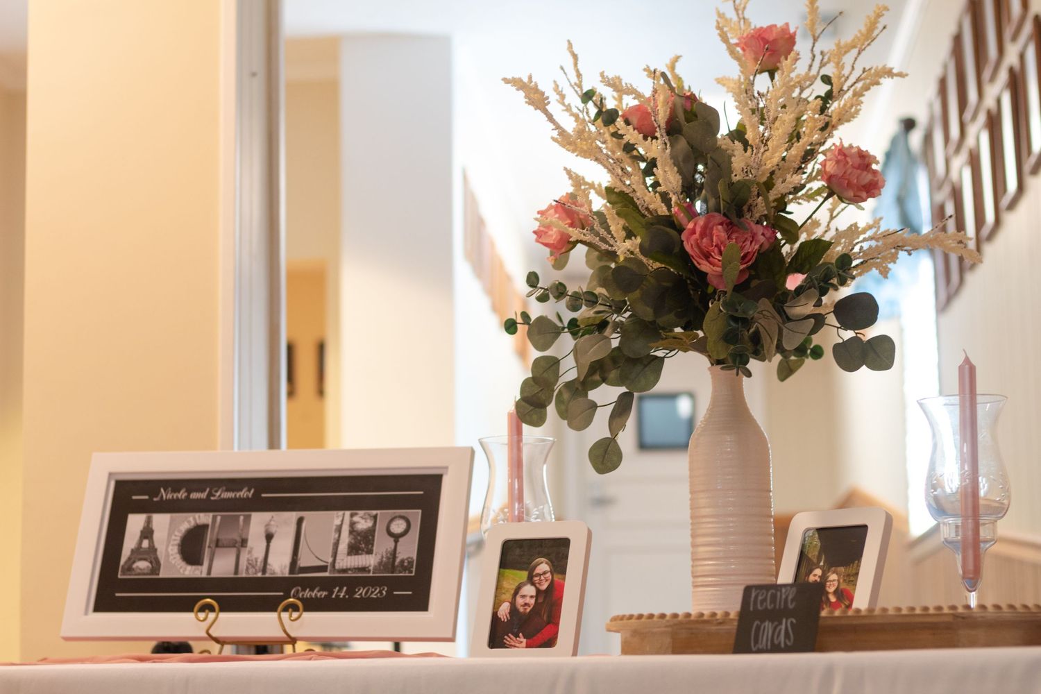 Table featured at wedding shower with flower arrangement and special photographs of the couple