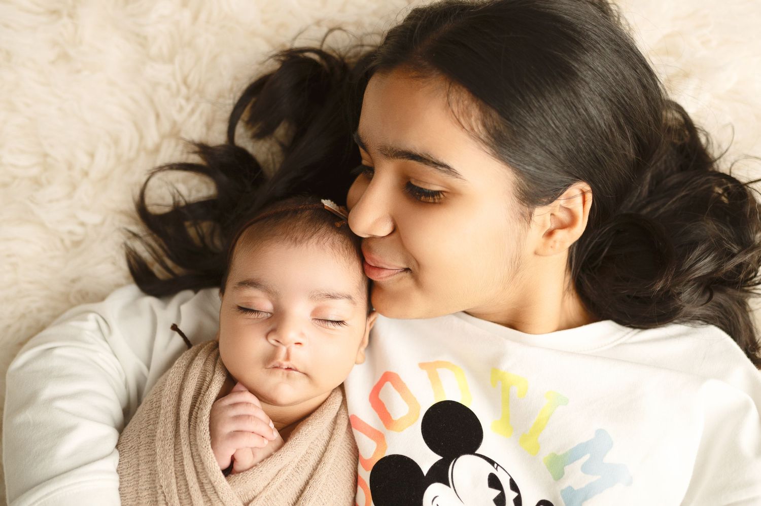 Sweet cuddle moment between parent and child on cozy white blanket.