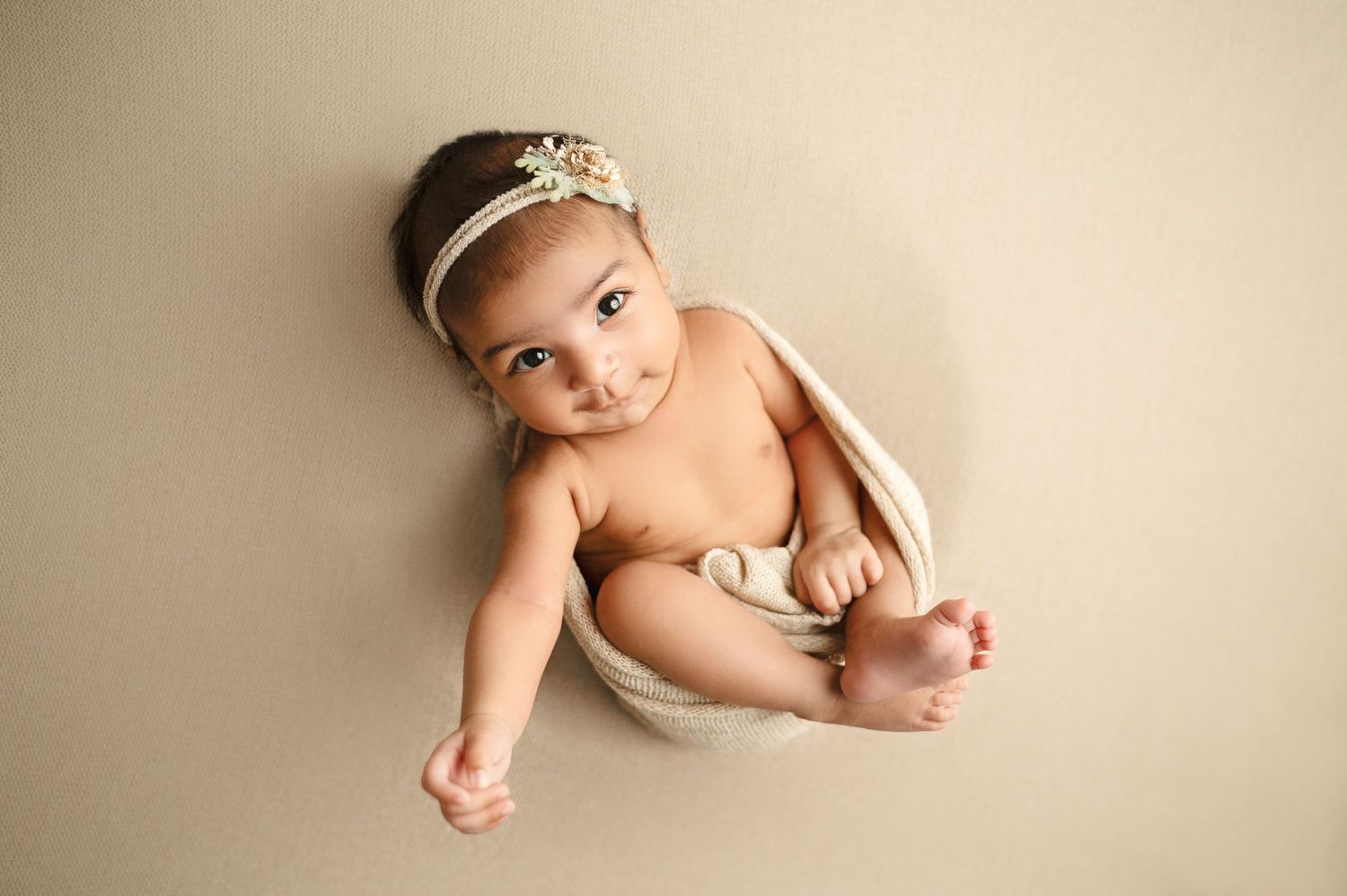 Artistic newborn portrait with sparkly headpiece on neutral background.