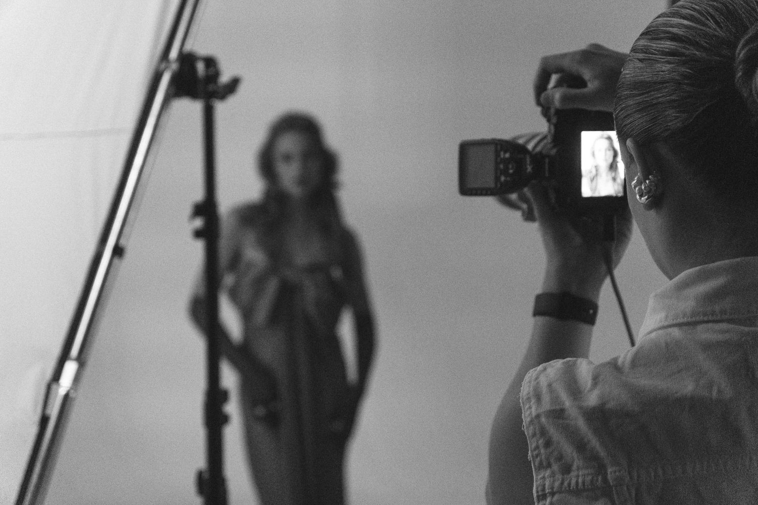Black and white photo of a photographer taking pictures of a female model in a professional studio setting.
