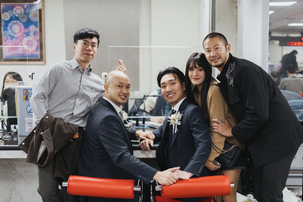 Group of five people posing and smiling together in an indoor setting, dressed in formal attire for a special occasion.